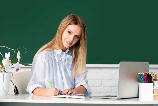 Portrait of smiling young college student writing, studying in classroom - Foto, Imagen