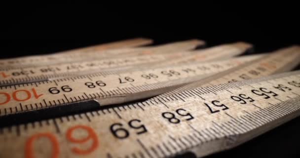 Regolo centimetro pieghevole in legno si trova sul tavolo scuro. Contatore di legno progettato per misurare la lunghezza su sfondo nero in studio - Filmati, video
