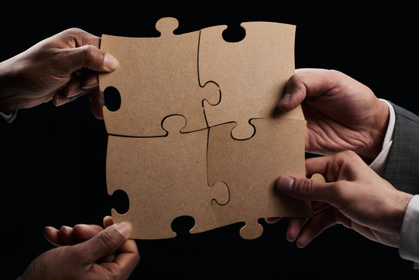 See the big picture. Close-up of an unknown business man holding three pieces of a puzzle together. - Zdjęcie, obraz