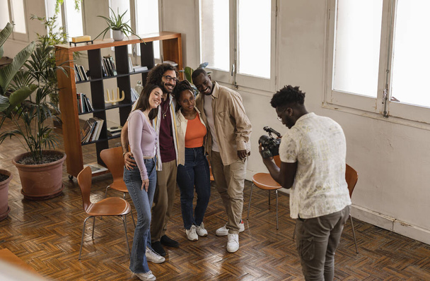 fotograaf registreert jonge ondernemers voor sociale media, groep multiraciale mensen in modern kantoor - Foto, afbeelding