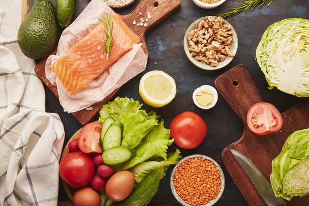  Ästhetisch gesunde futterarme Lebensmittel - Gemüse, Obst, Walnüsse, Räucherlachs, Gemüse, Avocado. Ansicht von oben. - Foto, Bild