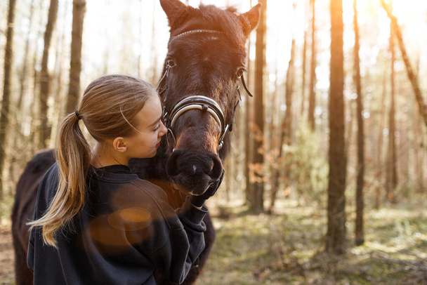 a young girl jockey hugs a horse. - Photo, Image