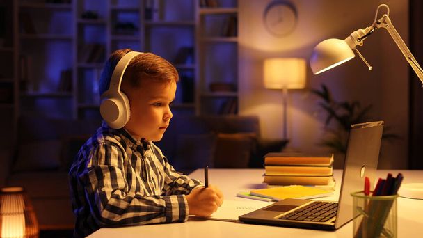 Cute boy student in headphones studying online from home, watching web lesson or listening to tutor via video call, e-learning on pandemic isolation. Distance education of children - Fotoğraf, Görsel