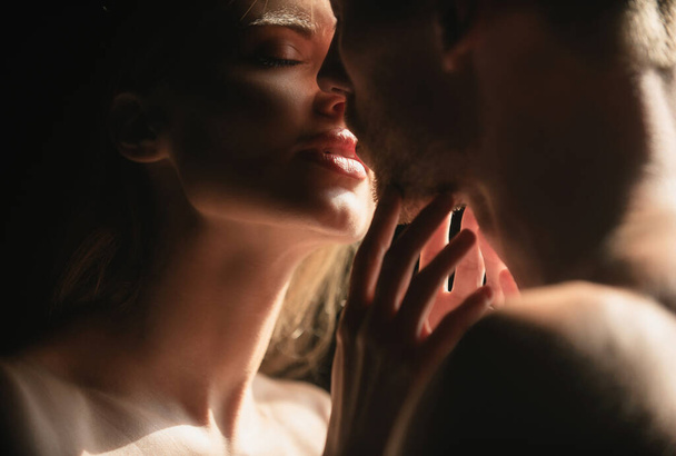 Sensual woman lips in the tender passion. Romantic couple in love looking at each other, embracing and kissing on black background - 写真・画像
