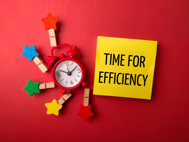 Будильник и деревянные зажимы со словом TIME FOR EFFICIENCY на красном фоне - Фото, изображение