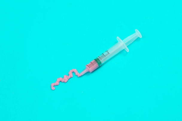 Syringe with pink liquid on blue background. Minimalism medicine concept - Foto, afbeelding