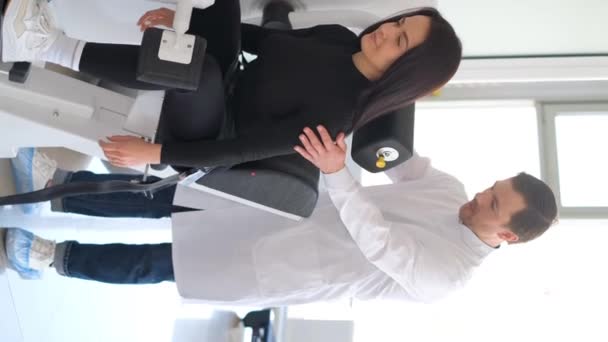 Vídeo vertical de um vertebrologista examinando um paciente em uma máquina tecnológica moderna. Prevenção de doenças da coluna vertebral. - Filmagem, Vídeo