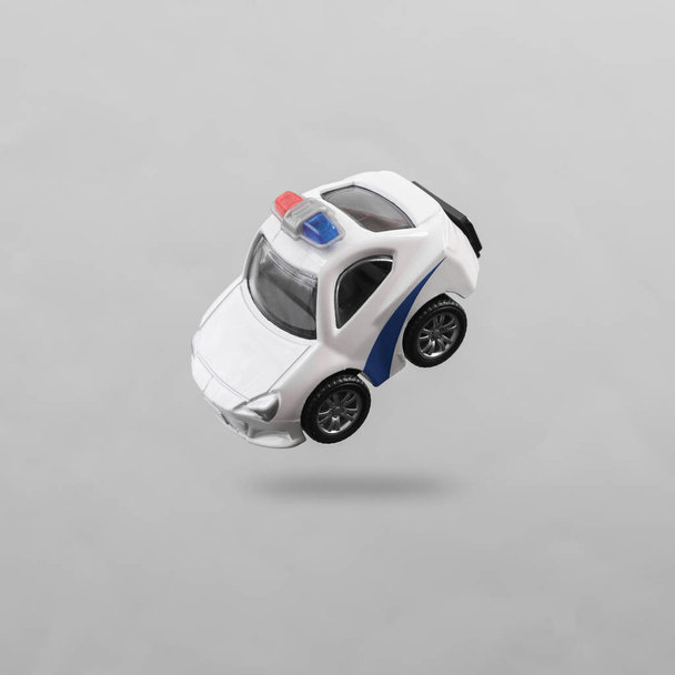 Toy police car levitating on gray background with shadow - Foto, afbeelding