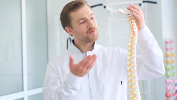 Вертебролог рассказывает, как лечить спину, показывая скелет позвоночника. Боль в спине - Кадры, видео