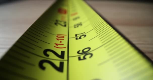 Pitkä keltainen senttimetri nauha-line venyttely puinen pöytä valmis mittaukseen. Hallitsija senttimetrin ja tuuman numeroilla ja jakeilla pituuden mittaamiseen - Materiaali, video