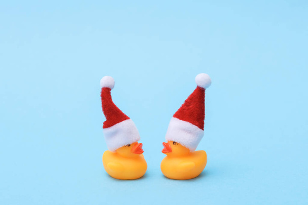 Dwie gumowe kaczki w kapeluszu Mikołaja na niebieskim tle. Koncepcja świąteczna - Zdjęcie, obraz