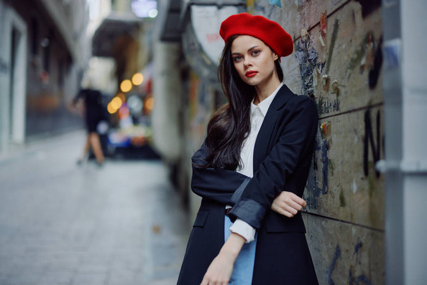 Модный женский портрет прогуливающегося туриста в стильной одежде с красными губами, идущего по узкой городской улице, путешествия, кинематографический цвет, ретро-винтажный стиль, драматизм. Высокое качество фото - Фото, изображение