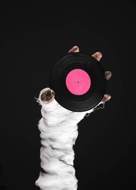 Mummy hand holding vinyl record isolated on black background. Halloween concept - Photo, Image