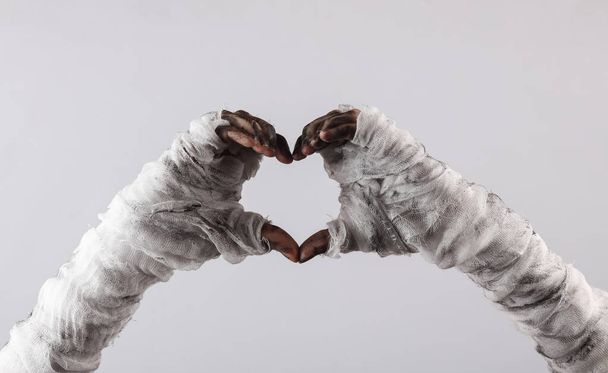 Mummy hands with folded fingers in the shape of a heart on a gray background - Foto, Bild