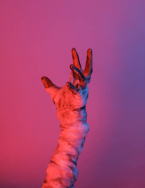 Maman main enveloppée dans un pansement dans la lumière du gradient néon. Concept Halloween - Photo, image