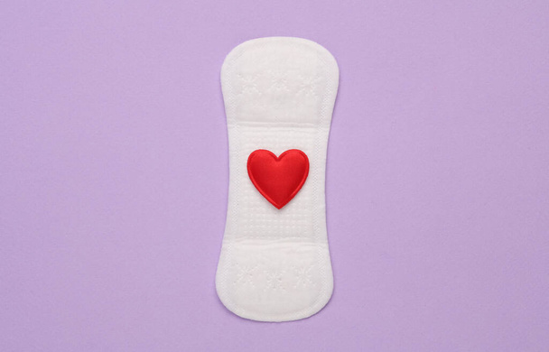 Pad with heart on a purple background.  Feminine intimate hygiene concept - Foto, afbeelding