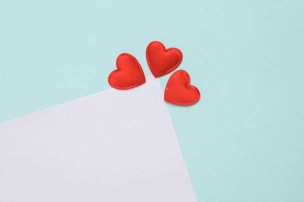 White paper sheet with hearts on blue background. Romantic, love concept, copy space - Photo, Image
