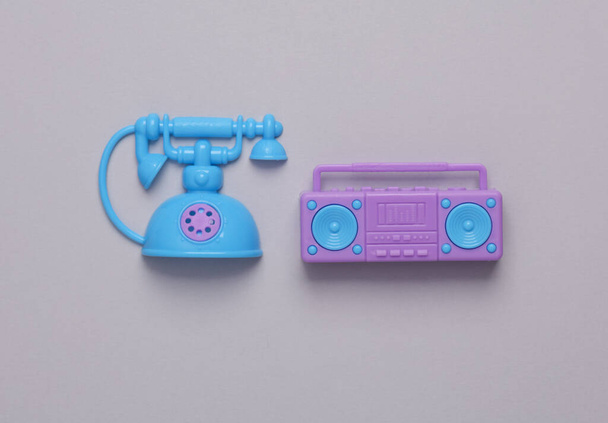 Іграшковий пластиковий магнітофон і поворотний телефон на сірому фоні
 - Фото, зображення