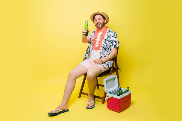 Hombre latino alegre haciendo contacto visual sonriendo mirando feliz diciendo vítores mientras bebe una cerveza en sus vacaciones de verano - Foto, imagen