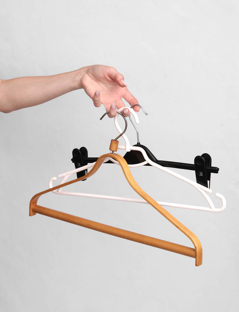 Woman's hand holds a lot of different hangers on a gray background - Photo, Image