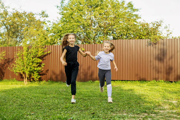Two children run in backyard in summertime. Childhood and vacation concept. - Photo, Image