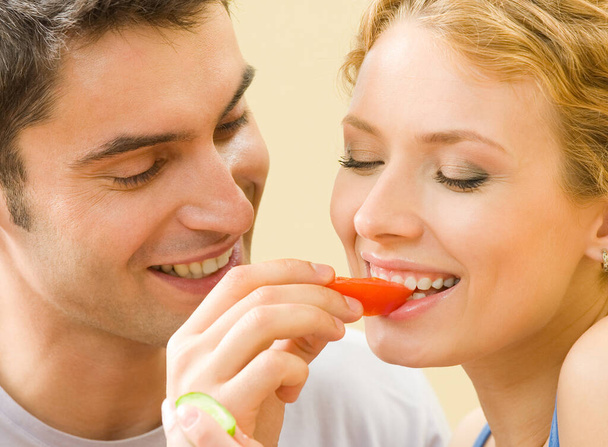 Cheerful young couple eating together tomatoes - Photo, Image