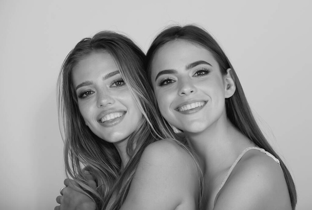 Portrait of two happy smiling cheerful young women. Two beautiful young women with perfect skin in the studio. Woman mouth with white teeth - Photo, Image