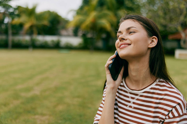 spacer kobieta mówi koszula natura inteligentny trawa sezonowe szczęśliwy odkryty blogger osoba palma komórka uśmiechnięty zielony rozmawiać człowiek telefon styl życia drzewo park - Zdjęcie, obraz