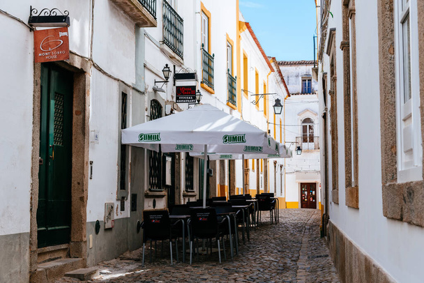 Evora, Portugal - June 30, 2022: Narrow street in the old town of Evora with restaurant terrace - Fotó, kép