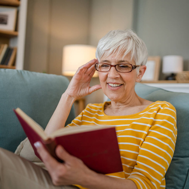 Una mujer madura mayor caucásica pensionista moderna abuela leer libro en casa gafas de desgaste espacio de copia persona real - Foto, imagen