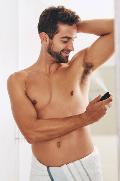 Deodorant, body spray and man in bathroom for hygiene, shower and perfume to control sweating. Happy shirtless guy cleaning armpit with fragrance cosmetics, mist and skincare product for male beauty. - Valokuva, kuva