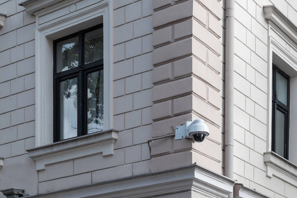 A modern security video surveillance camera on the wall of a masonry building. CCTV camera attached to the wall of the house. - Photo, Image