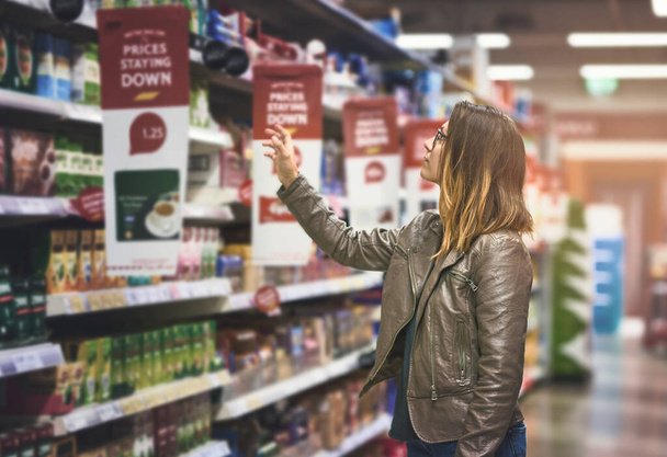 Shopping, woman at grocery store and in aisle searching and decision for product on a shelf. Customer or consumer, shopper for groceries and female person at supermarket or a shop looking for food. - Zdjęcie, obraz