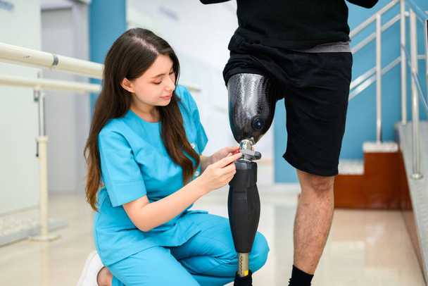 Жінка-фізіотерапевт, що налаштовує протезну ногу пацієнта в лікарні, інвалідний пацієнт з лікуванням у медичному центрі, Нове виробництво штучних кінцівок для інвалідів
 - Фото, зображення