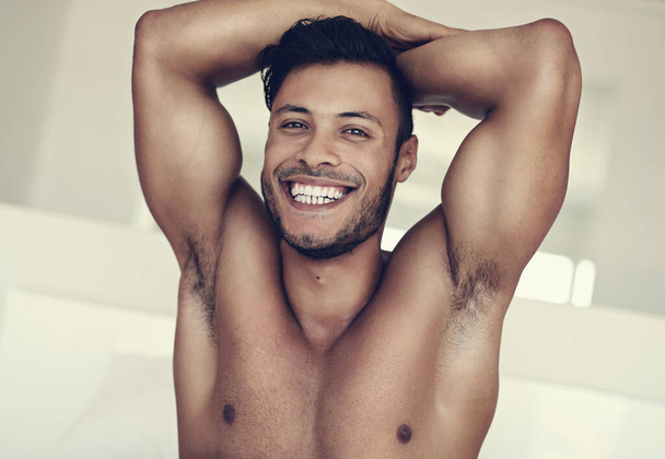 Hymyile, muotokuva yläosattomasta nuoresta miehestä ja hänen talonsa makuuhuoneessa. Itsehoito tai ylpeä kasvot, luottavainen tai positiivinen ajattelutapa ja paidaton miesmalli, jossa lihasten terveys tai hyvinvointi kotona Brasiliassa. - Valokuva, kuva