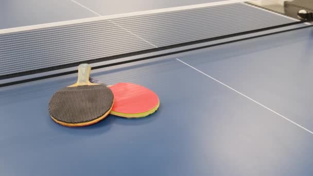Racchette professionali e palla su un tavolo da ping pong blu. Pubblicità Ping Pong. - Filmati, video