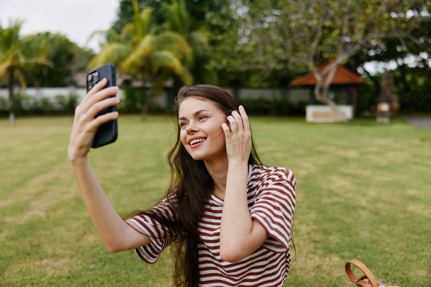 mens vrouw natuur park persoon cel student lente glimlachen gras gelukkig mobiel jong glimlach meisje palm seizoensgebonden blogger werken levensstijl boom telefoon - Foto, afbeelding