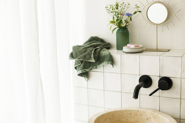 Belles fleurs dans la salle de bain moderne avec lavabo élégant, robinet noir et carreaux blancs. Arrangement de fleurs d'été recueillies du jardin dans la chambre moderne dans la maison - Photo, image