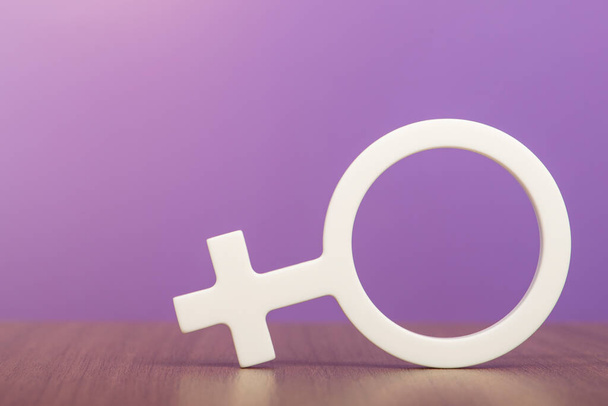Gender-Symbol einer Frau. Frau Symbol auf lila Hintergrund mit Kopierraum. Das Konzept einer weiblichen Führungskraft oder die Gleichberechtigung der Geschlechter. Hochwertiges Foto - Foto, Bild