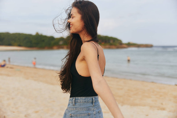χαμόγελο γυναίκα διακοπές παραλία ηλιοβασίλεμα θάλασσα αναψυχή φόρεμα άμμο χαμογελώντας υπαίθρια χαλαρώστε ξέγνοιαστα μαλλιά jean μακρύ καλοκαίρι φύση ωκεανός lifestyle νερό ευτυχισμένη - Φωτογραφία, εικόνα
