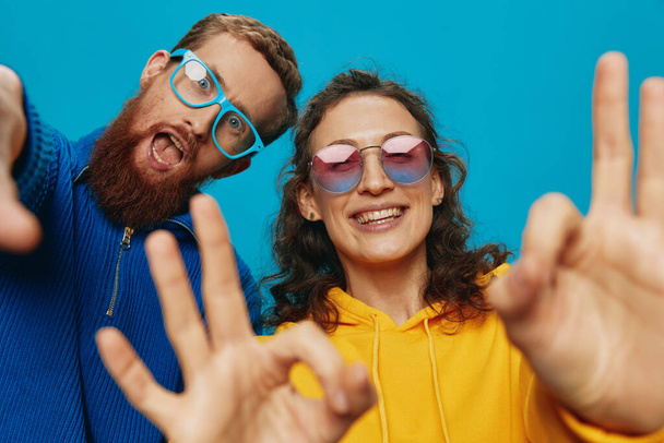 Une femme et un homme couple amusant manivelle et montrant des signes avec leurs mains souriant joyeusement, sur un fond bleu, Le concept d'une vraie relation dans une famille. Photo de haute qualité - Photo, image