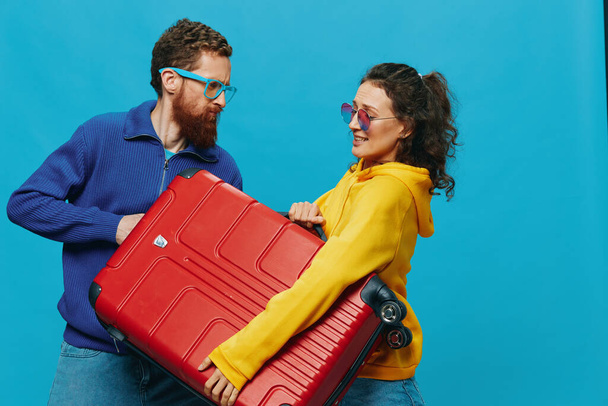 Woman and man smile suitcases in hand with yellow and red suitcase smile fun, on blue background, packing for a trip, family vacation trip. High quality photo - Photo, Image