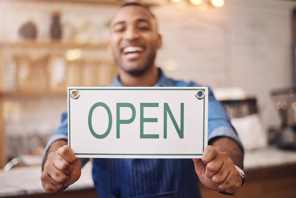 Open, sign and closeup of man in shop, store and advertising notice of retail shopping time, board or trading information. Hands of happy cafe owner with opening banner, welcome and startup services. - Foto, imagen
