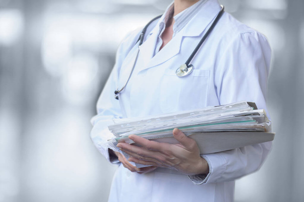 Doctor with folders about case histories the patient stands on a blurred background. - Photo, image