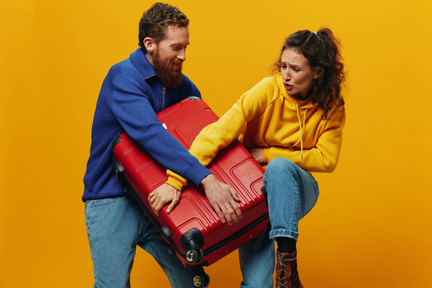 Woman and man smiling, suitcases in hand with yellow and red suitcase smiling merrily and crooked, yellow background, going on a trip, family vacation trip, newlyweds. High quality photo - Photo, Image