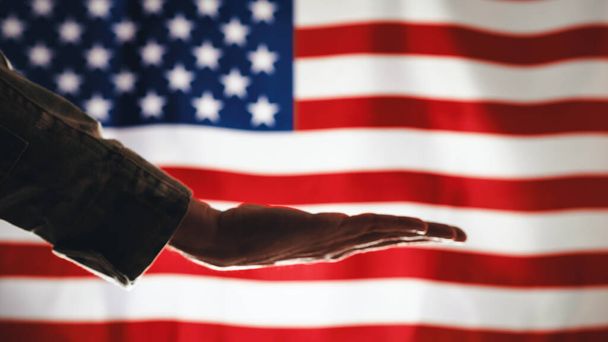 Hand des Militarismus hält Plakette gegen amerikanische Flagge zum Gedenktag. - Foto, Bild