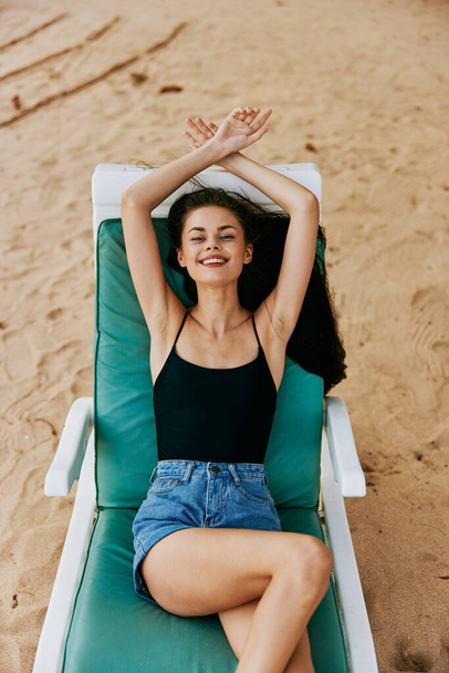 sininen nainen bikinit keinona hiekka makaa tuoli hymyilevä ranta loma elämäntapa hattu valtameri matkustaa istuu aurinko solarium ranta meri uimapuvut trooppinen - Valokuva, kuva