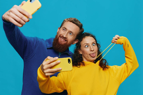 女性と男の面白いカップル 手で携帯電話を取るセルフィー ブルーの背景で笑顔の楽しみ. 実際の家族関係の概念,電話で話す,オンラインで動作する. 高品質の写真 - 写真・画像