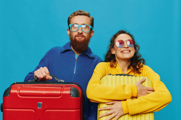 Mulher e homem sorrir malas na mão com amarelo e vermelho mala sorrir diversão, no fundo azul, a embalagem para uma viagem, viagem de férias em família. Foto de alta qualidade - Foto, Imagem