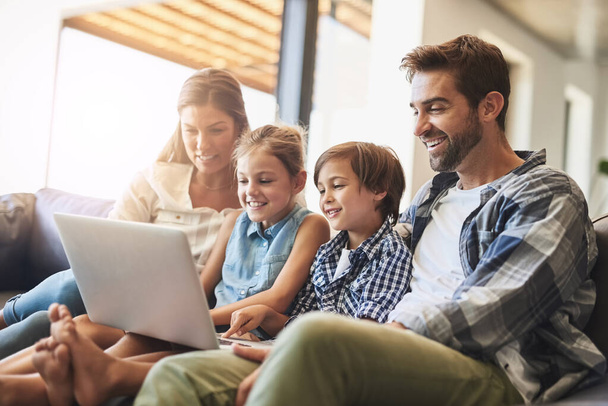 Famiglia, laptop e bambini sorridono con i genitori su un divano soggiorno con gioco di istruzione online. Mamma, papà e bambini piccoli insieme a legame, cura e amore in una casa in streaming di un video sul computer. - Foto, immagini